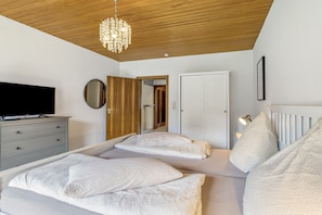Une chambre à coucher comprenant un lit, une commode, un téléviseur et un lustre.