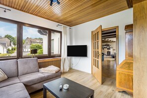 Una sala de estar moderna con sofá, una mesa de centro, un televisor de pantalla plana montado en la pared y un mueble de madera.