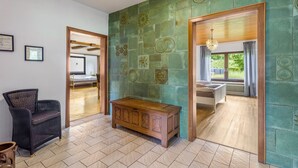 Quarto com um banco de madeira, uma cadeira de vime e parede com azulejos verdes.