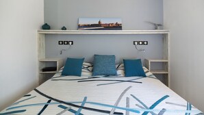 Ein Schlafzimmer mit einem Bett, einem an der Wand befestigten Regal mit einem Bild und Nachttischen.