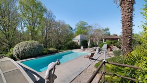 Ein Swimmingpool mit einer Pergola, einer Palme und einem Gebäude im Hintergrund.