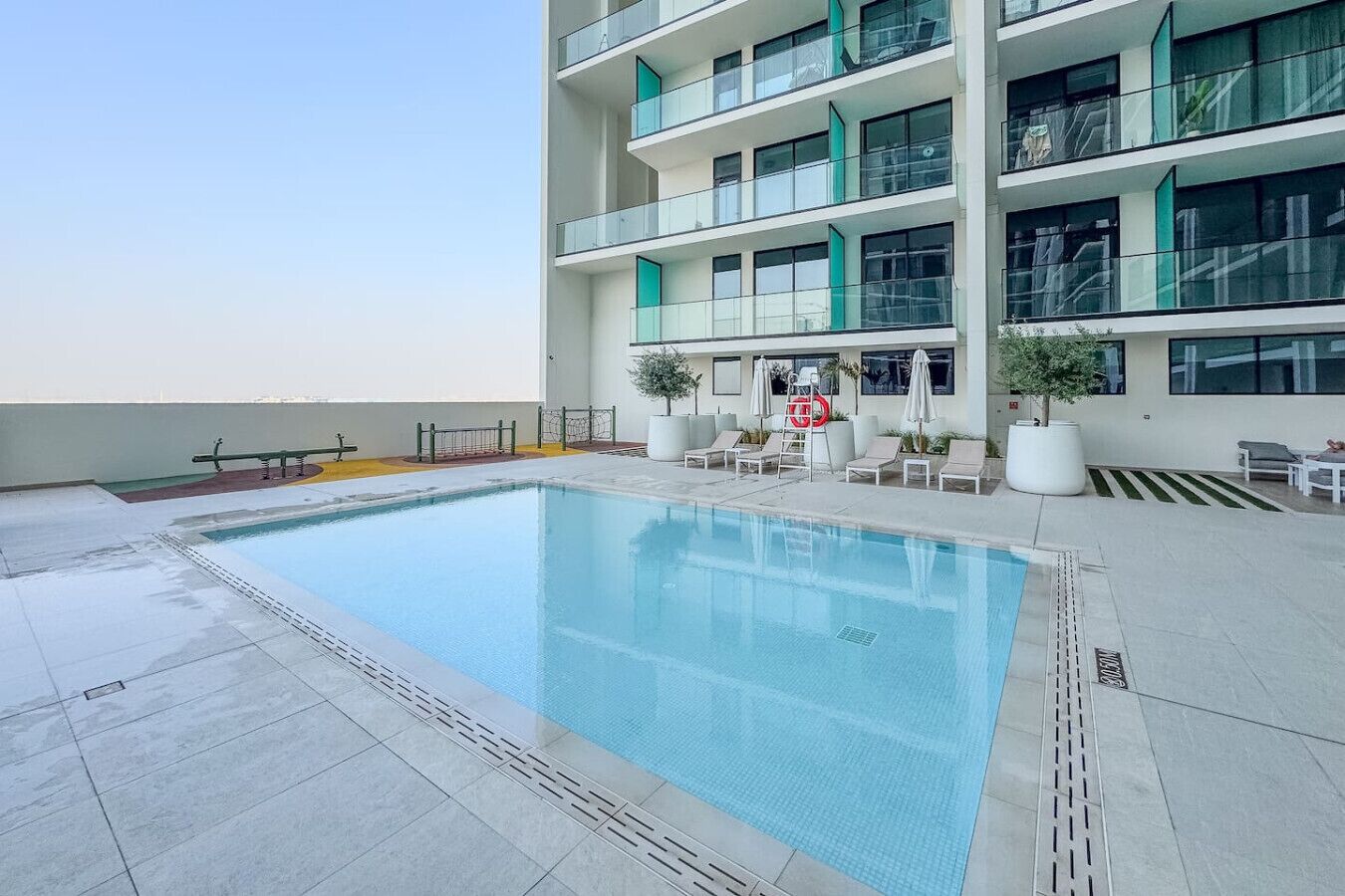 Un edificio moderno con piscina sul tetto, area salotto all'aperto e piante in vaso.