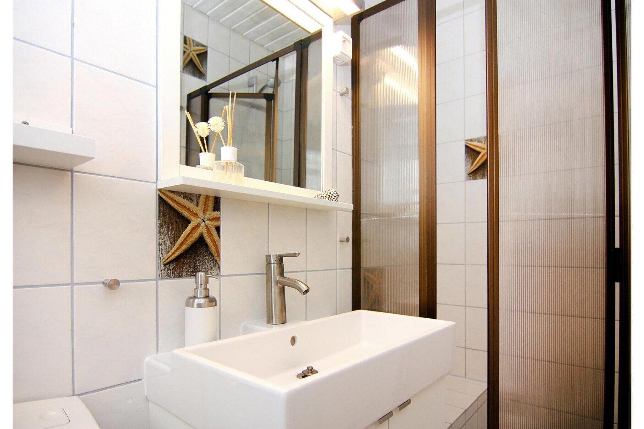 Een moderne badkamer met een witte wasbak, een spiegel en een zeester decoratie aan de muur.