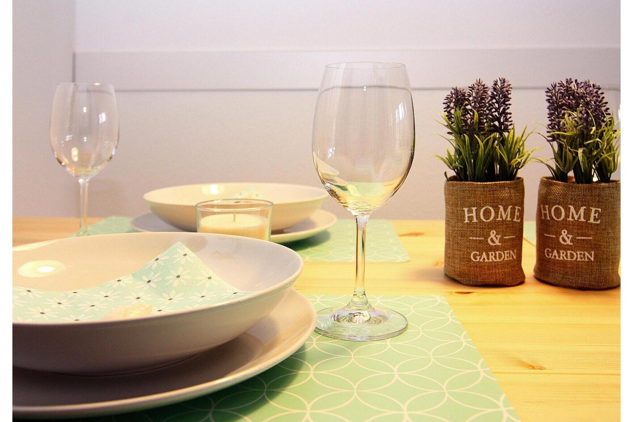 A dining table with two bowls, two wine glasses, and two small potted plants labeled "HOME & GARDEN".