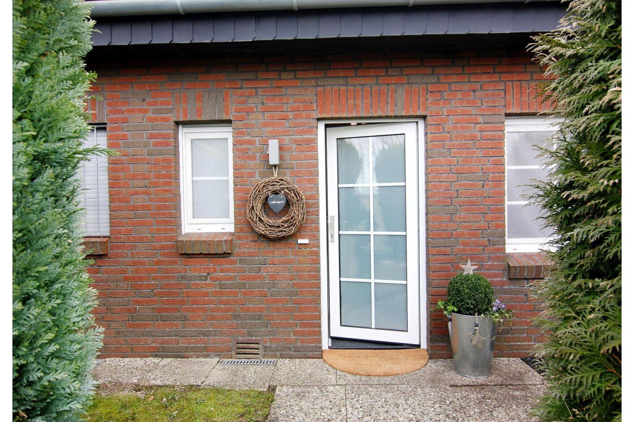 A brick house with a white door, a small window, and a wreath on the wall.