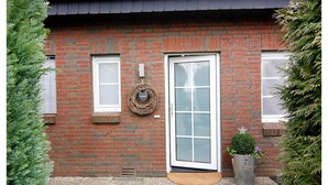 Una casa in mattoni con una porta bianca, una piccola finestra e una ghirlanda al muro.