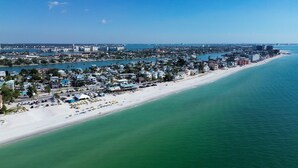 A coastal cityscape with a wide beach, clear blue waters, and dense residential buildings along the shoreline. - Rocking Sunset Beach House (Treasure Island)