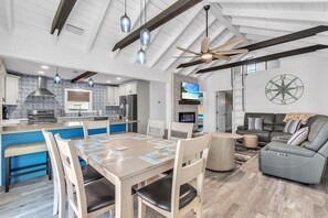 A spacious living area with a dining table, chairs, a sofa, and a ceiling fan. - Rocking Sunset Beach House (Treasure Island)