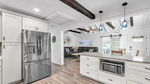 A modern kitchen with white cabinetry, stainless steel appliances, and a central island. - Rocking Sunset Beach House (Treasure Island)