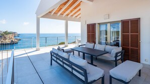 A covered outdoor seating area with a view of the sea. - Can Ferrando House with Sea Views, Wi-Fi and Air Conditioning (Cala Santanyi - Santanyi)