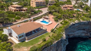 A coastal property with a swimming pool, a large building with a balcony, and a cliff overlooking the sea. - Can Ferrando House with Sea Views, Wi-Fi and Air Conditioning (Cala Santanyi - Santanyi)