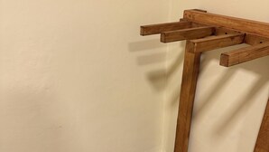 Um canto com um banco de madeira e uma pequena mesa encostada a uma parede lisa.