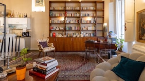 A spacious living room with a large bookshelf, a dining area, and a cozy seating arrangement. - Hotiday Cagliari Porto (Cagliari)