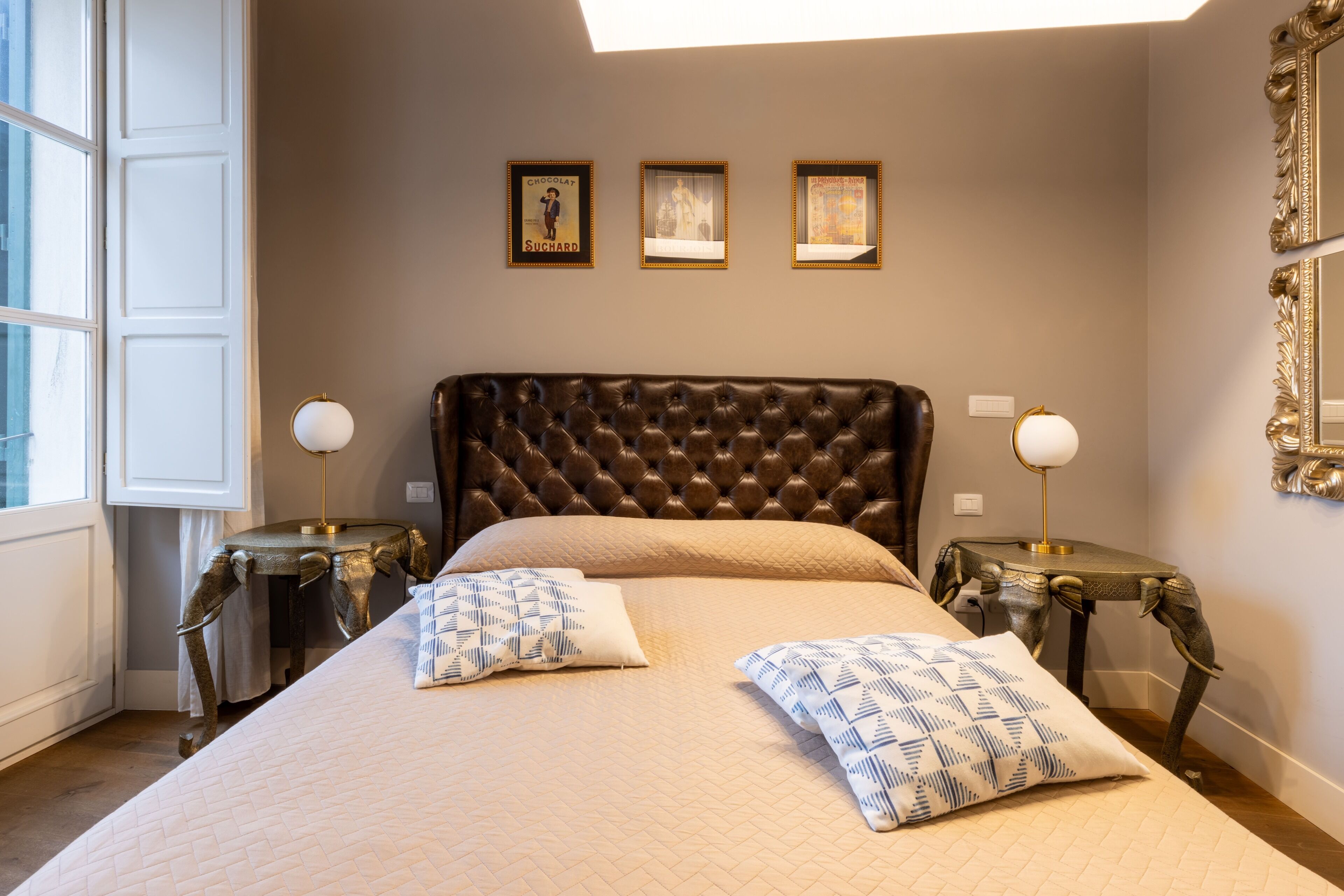 A bedroom with a large bed, two nightstands, and three framed pictures on the wall.