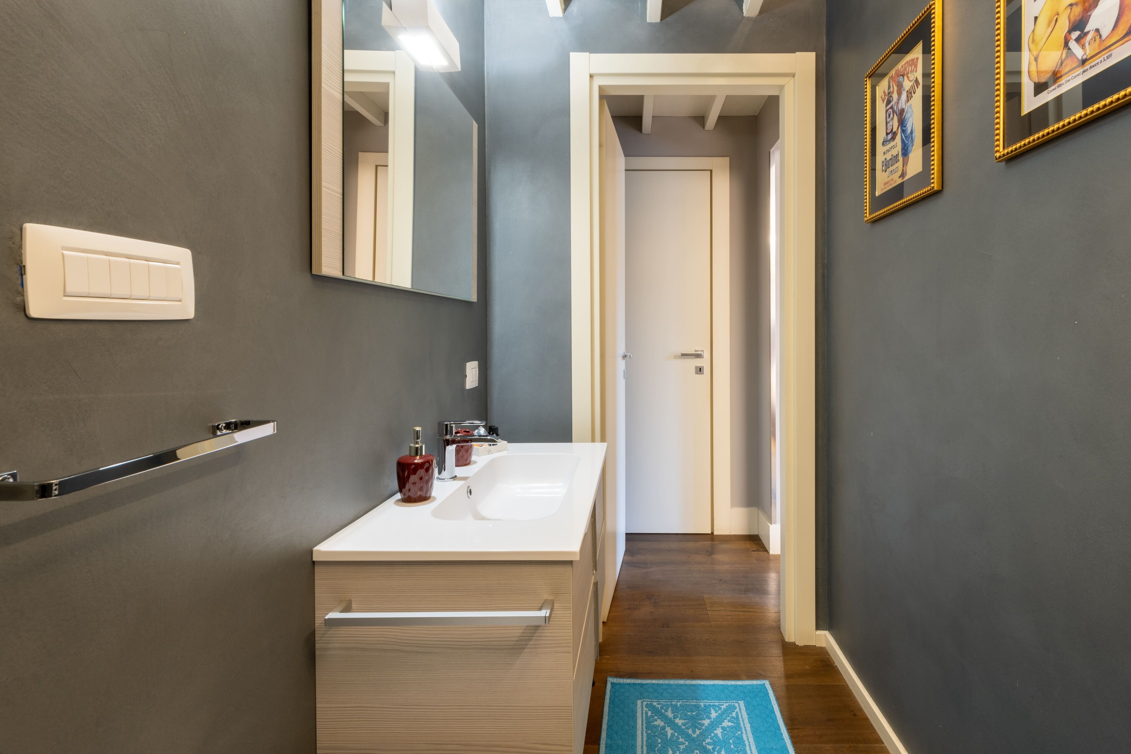 Une salle de bain moderne avec un lavabo blanc, un miroir et un porte-serviettes.