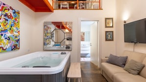 A modern living room with a large bathtub, a sofa, and a television. - Hotiday Cagliari Porto (Cagliari)