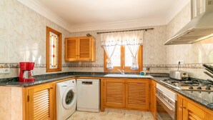 A kitchen with wooden cabinets, a washing machine, a stove, and a sink. - Holiday Home 'Sa Trona' with Sea Views, Private Terrace and Wi-Fi (Cala Santanyi - Santanyi)