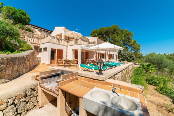 Una villa con piscina, area relax esterna e un muro in pietra.