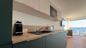 Une cuisine moderne dotée d’un évier encastré, d’une machine à café et d’un téléviseur à écran plat placé au-dessus du plan de travail.