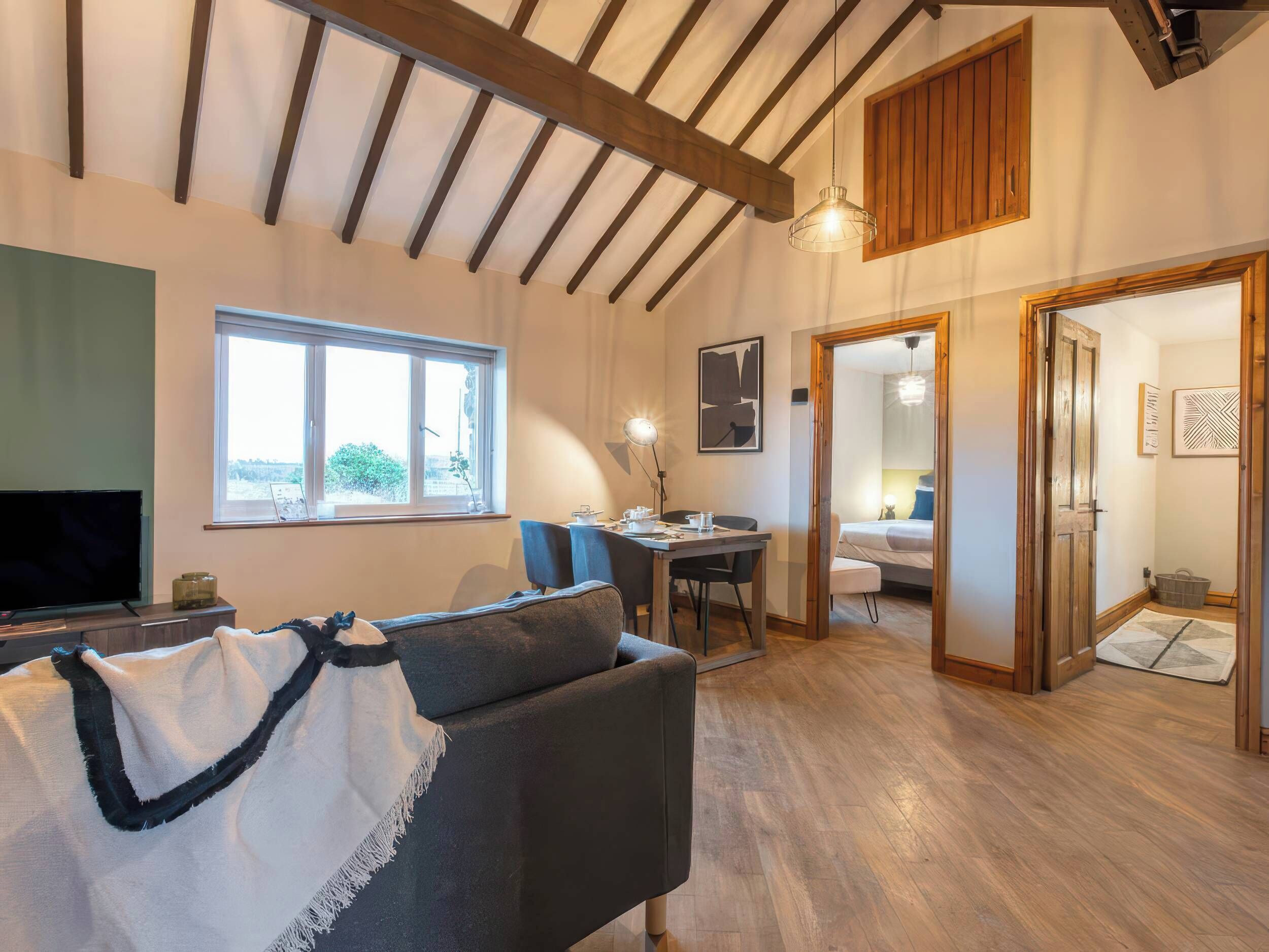 Una sala de estar acogedora con un sofá, un televisor y un comedor con una mesa y sillas.