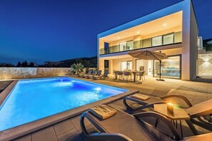 A modern two-story building with a swimming pool, outdoor seating, and a dining area. - Villa Cissa (Stara Novalja)