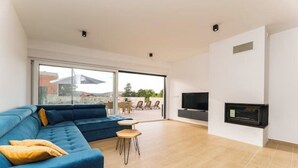 A modern living room with a blue sofa, a small wooden table, and a flat-screen TV mounted on the wall. - Villa Cissa (Stara Novalja)