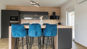 A modern kitchen with a central island, bar stools, and a pendant light. - Villa Cissa (Stara Novalja)