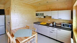 A compact kitchen with wooden cabinetry, a dining table, and basic appliances. - Spacious holiday homes with terraces, Sarbinowo (Sarbinowo)