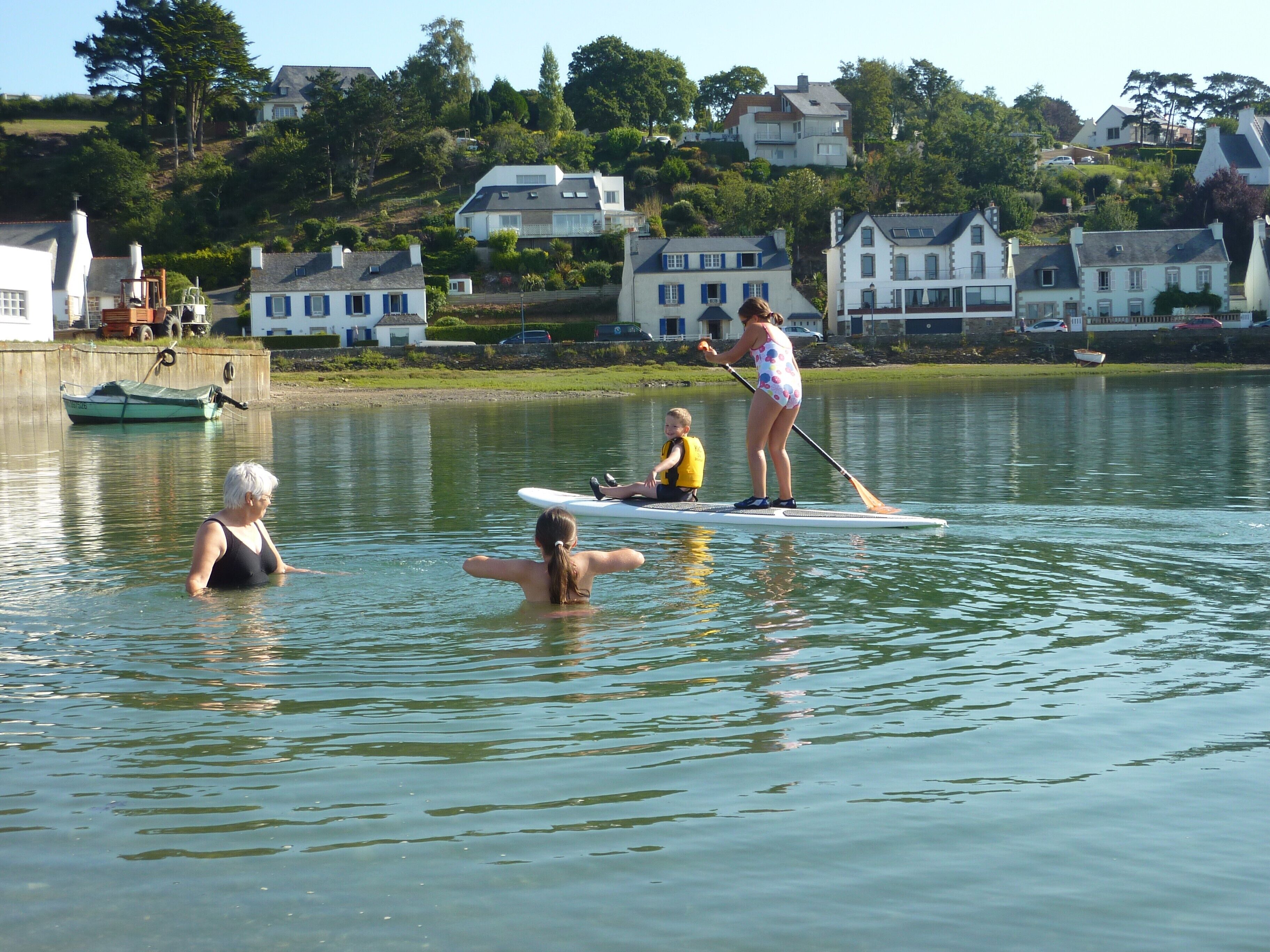Un lac paisible où l’on peut faire du paddle, avec une barque à rames et des maisons en arrière-plan.