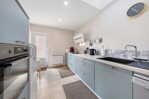 A modern kitchen with a built-in oven, a dishwasher, and a large window. - Holiday Home "Ty Gwen - Plouezoc'h" with Sea View and Wi-Fi (Plouezoc'h)