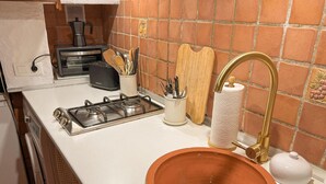 Een koffiezetapparaat/waterkoker, een koelkast, een oven, een kookplaat
