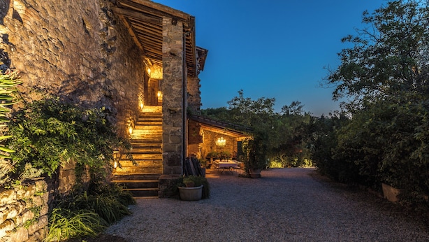 Un bâtiment en pierre avec une allée de gravier menant à une porte en bois.