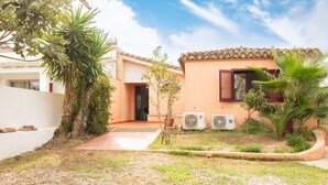 A residential property with a paved courtyard, two air conditioning units, and a small garden with palm trees. - Waves Apartment, only 250m from the sea  (Tortolì)