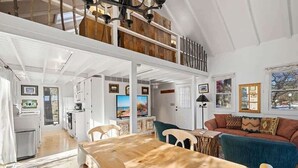 Een ruime woonruimte in loft-stijl met een eettafel, een bank en een keuken op de achtergrond.