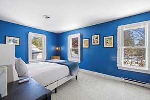 Un dormitorio con cama, mesita de noche, lámpara y ventana con persianas.