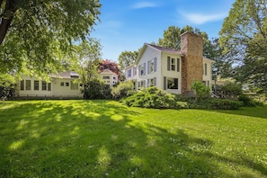 A two-story house with a brick chimney, surrounded by a well-maintained lawn and trees. - Juniper Presents: 33 Acre Berrywood Farm, 3 Home Retreat with Pool (Three Oaks)