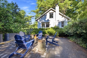 A house with a chimney, surrounded by trees and a patio with Adirondack chairs and a fire pit. - Juniper Presents: 33 Acre Berrywood Farm, 3 Home Retreat with Pool (Three Oaks)
