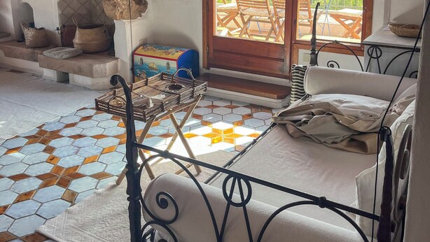 Una habitación acogedora con cama, una parrilla y vistas a una terraza con sillas y una mesa.