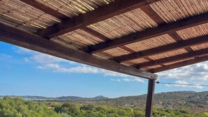 Un espacio de estar al aire libre con techo, con sofá y mesa, con vistas a un paisaje pintoresco.