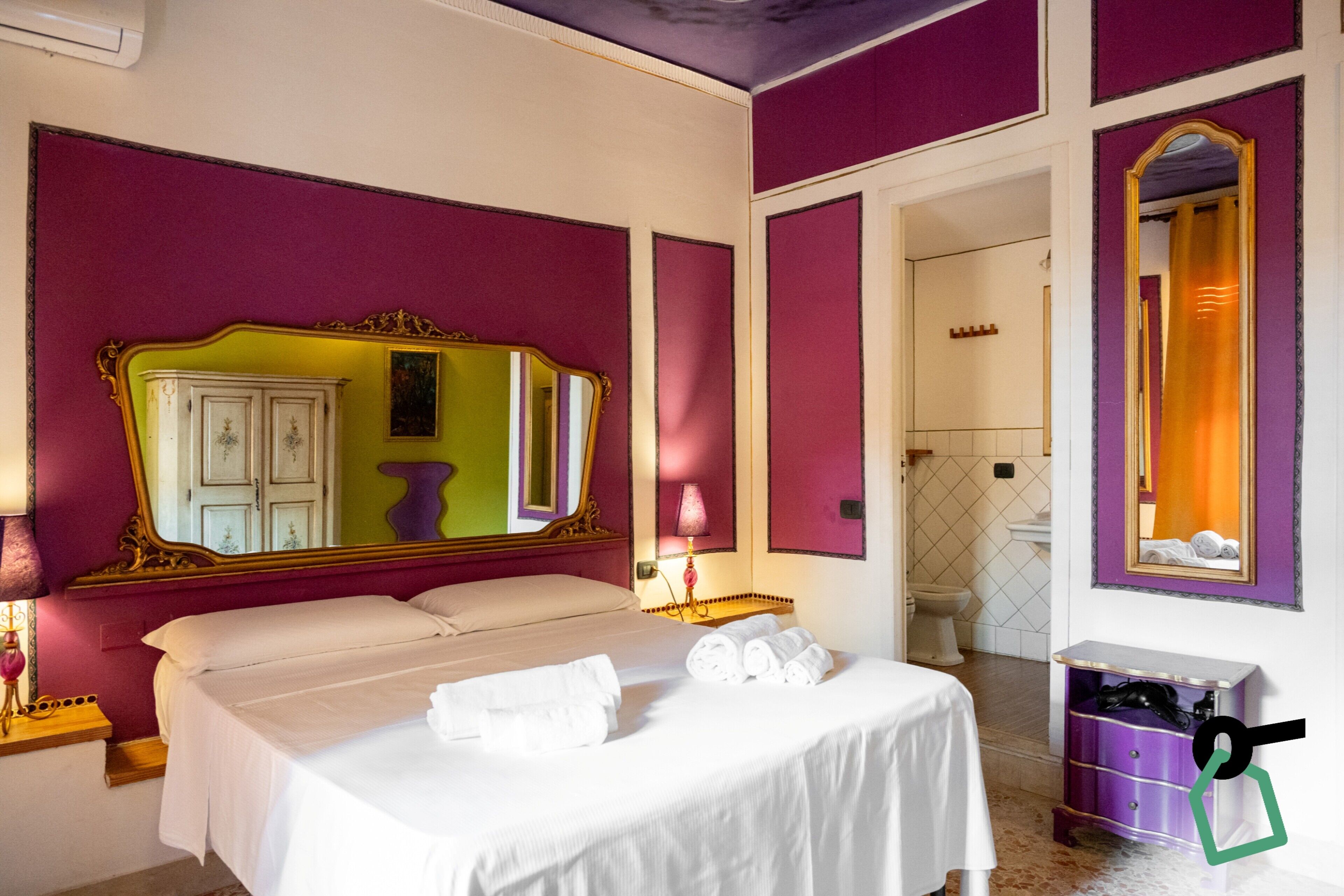 Ein Hotelzimmer mit einem großen Bett, einem Schminktisch mit Spiegel und einem durchgegangenen Tür sichtbar erkennbaren Badezimmer.