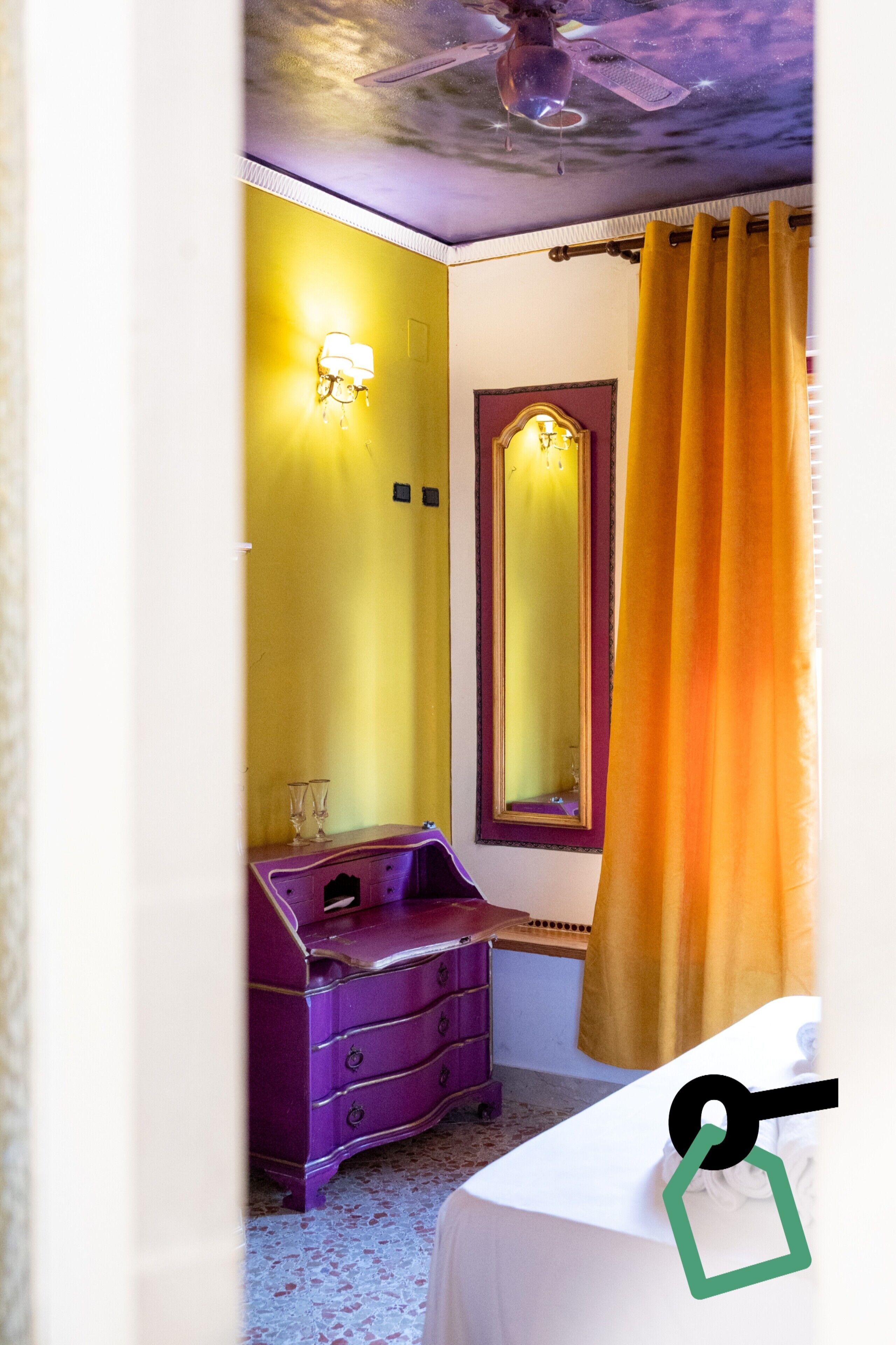 A room with a purple dresser, a mirror, and a yellow wall.