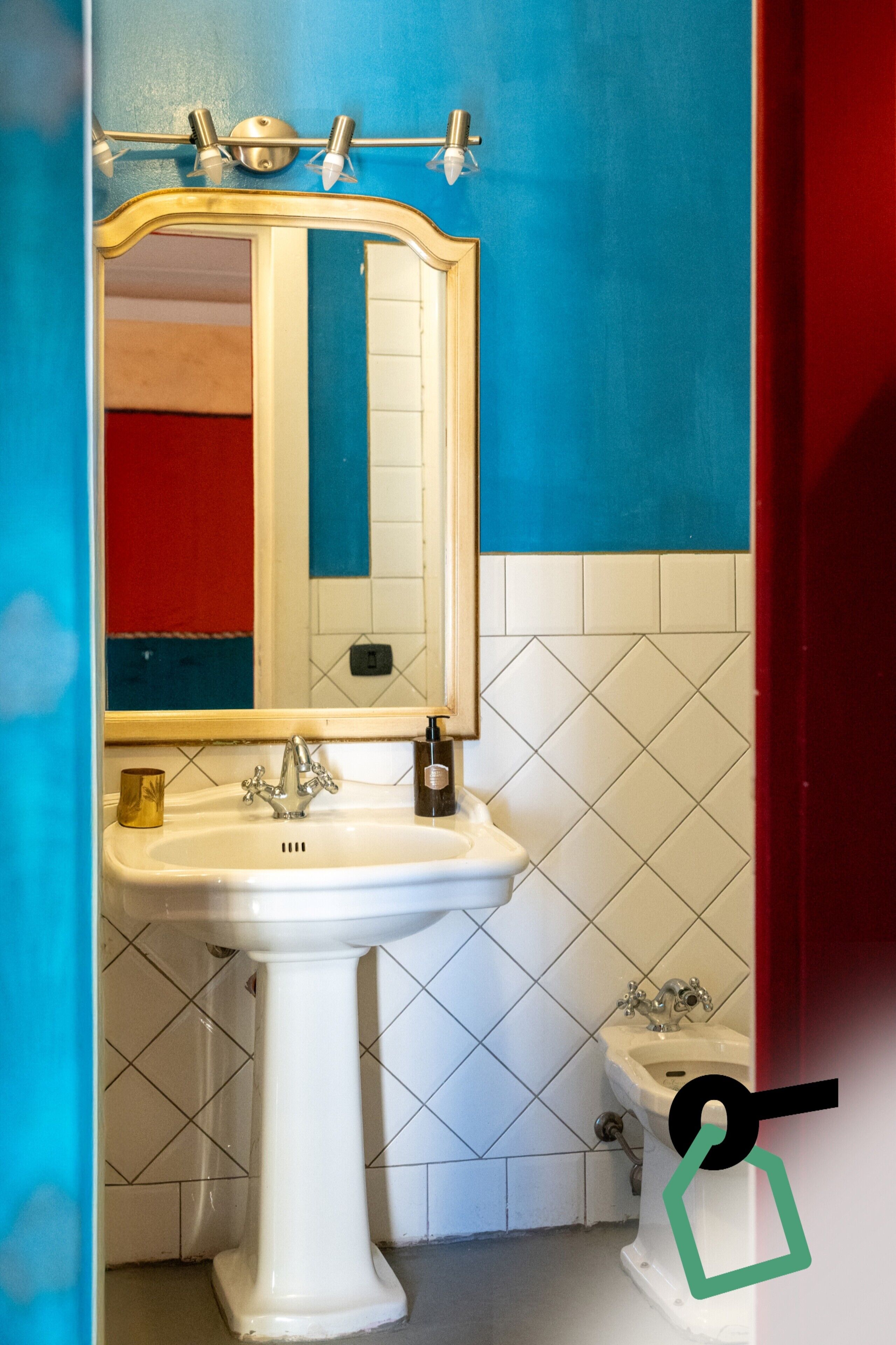 Een badkamer met een wit wastafeltje, een spiegel en een toilet.