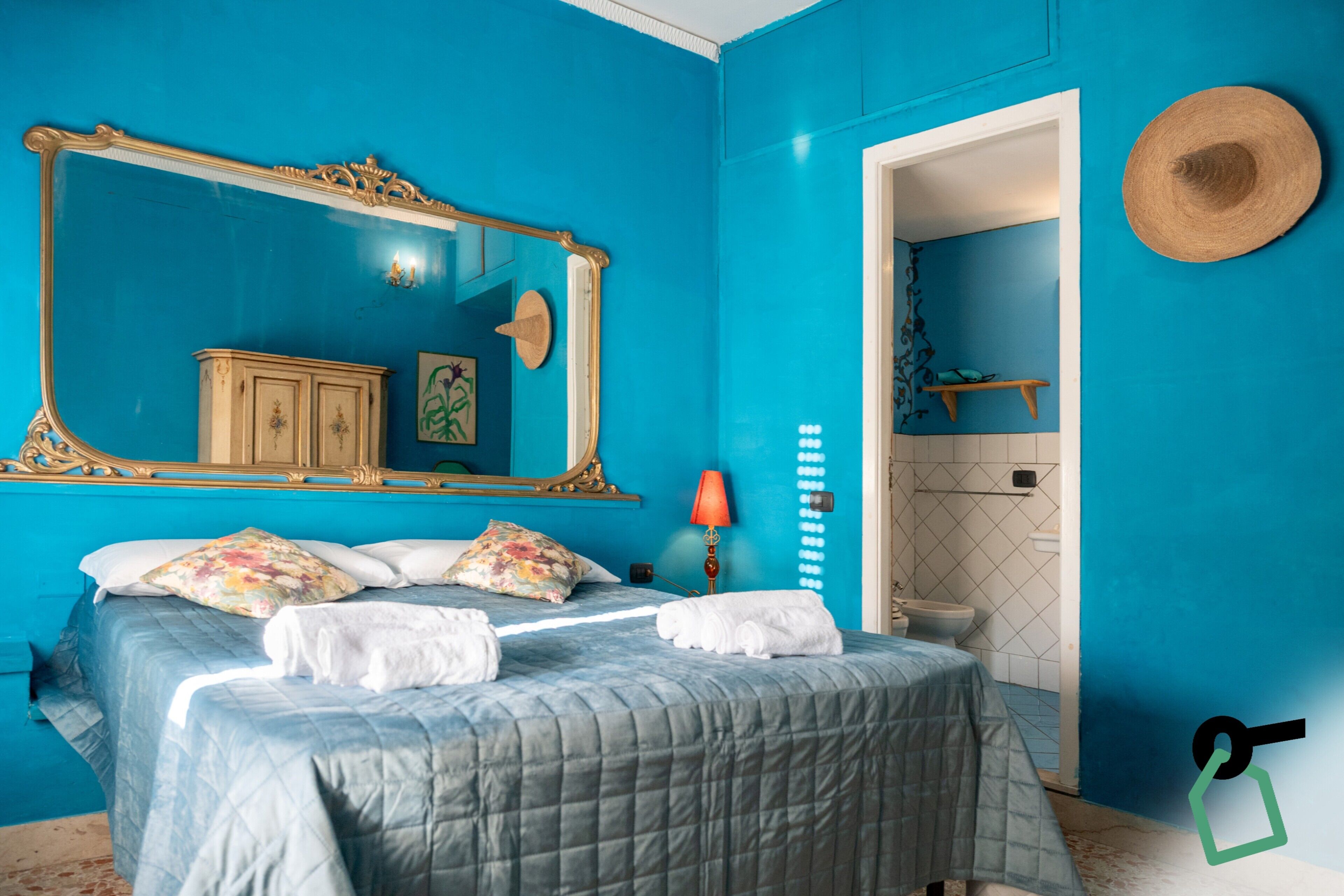 A room with a large bed, a mirror, a wardrobe, and a bathroom with a toilet and sink.