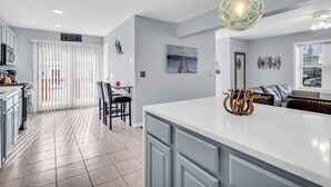 Una cocina moderna con una isla grande, una zona de comedor con sillas y vistas al mar por la ventana.