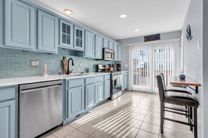 A modern kitchen with light blue cabinets, a white countertop, and a stainless steel dishwasher. - Seaside Park Beach Home | 3BR w/ Deck, Peloton, Parking + 6 Beach Passes (Seaside Park)