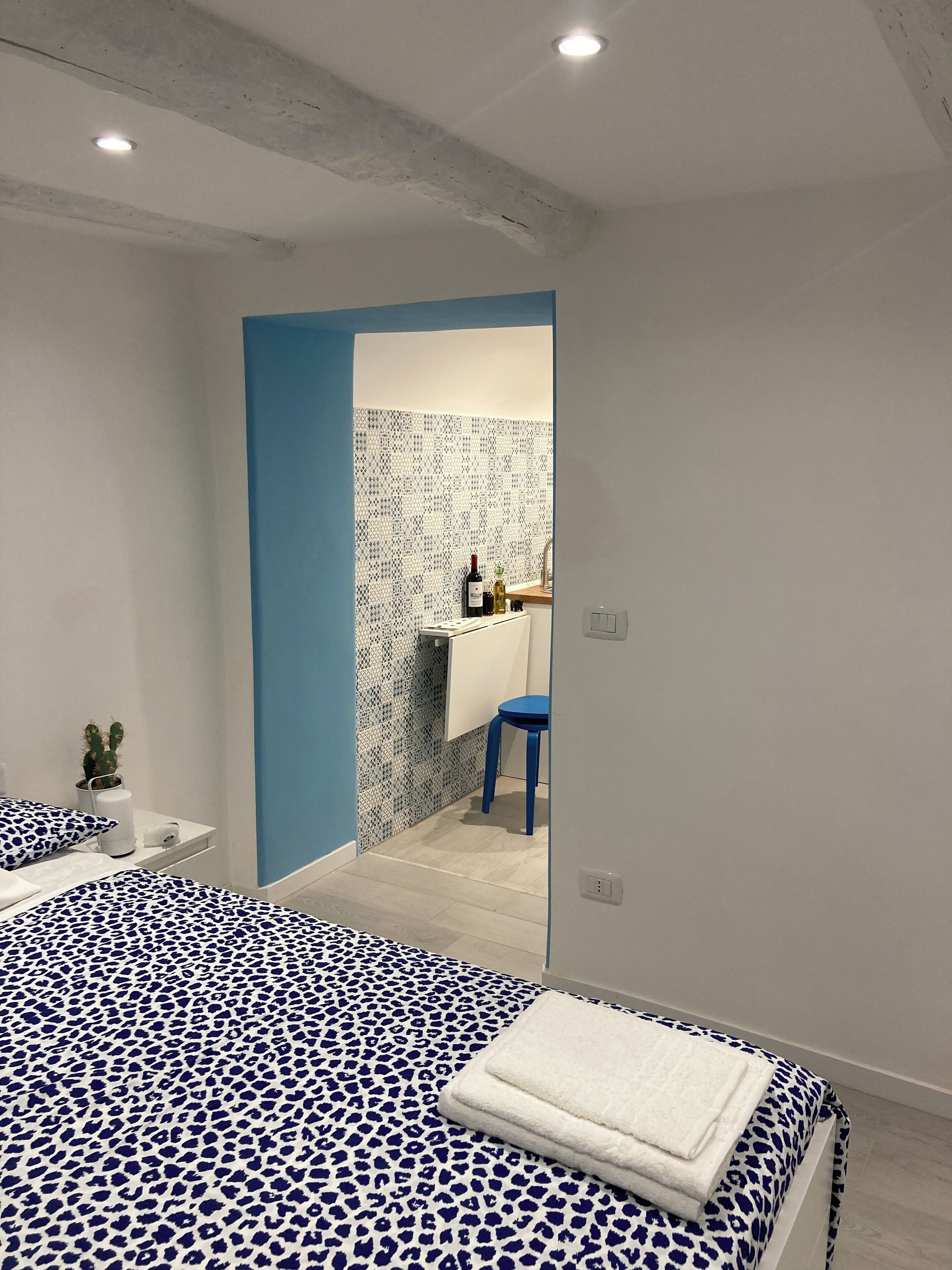 Ein modernes Schlafzimmer mit einem großen Bett, einem kleinen Schreibtisch und einem durchgegangenen Tür erkennbaren Badezimmer.