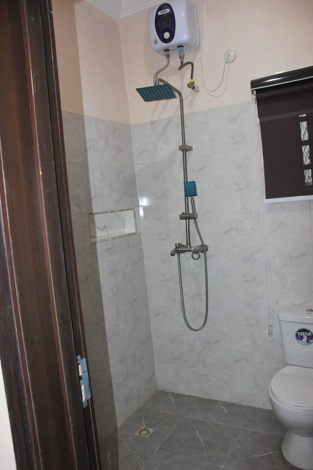 Ein Badezimmer mit Dusche, Toilette und Wandseifenspender.