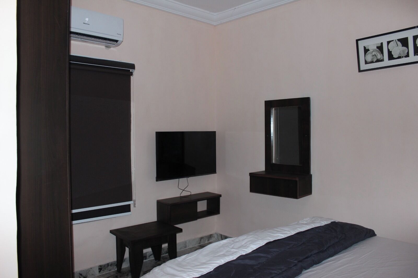 Een slaapkamer met een bed, een televisie, een spiegel, een bureau en een airconditioner.