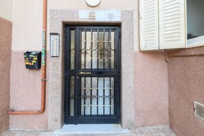 A black metal gate with a number "69" above it, a utility box to the left, and a window with shutters to the right. - M Gco69bd Apartamento de 3 Dormitorios (Madrid)