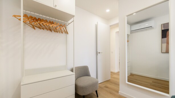 Une chambre moderne dotée d’une armoire intégrée, d’un coin salon et d’un grand miroir.